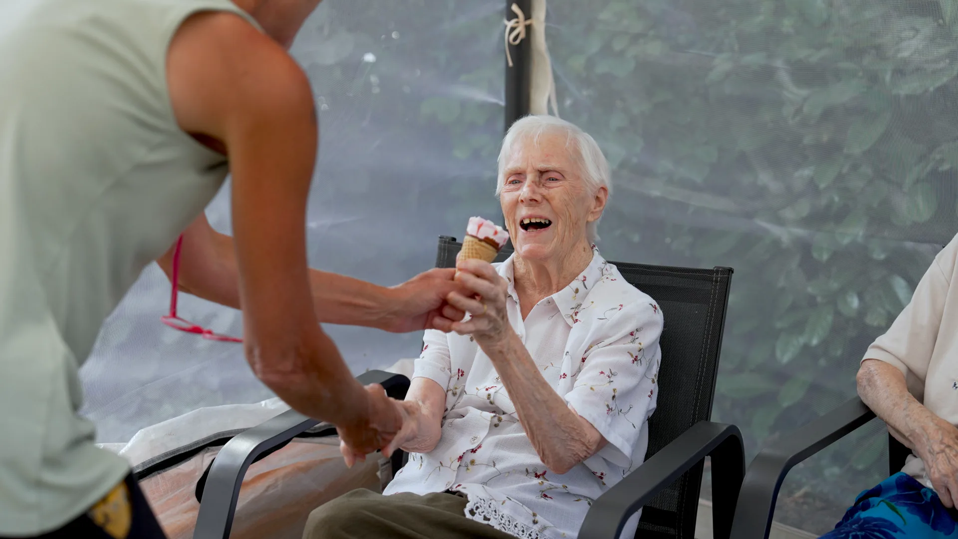 A carer laughing with a resident while serving ice cream.