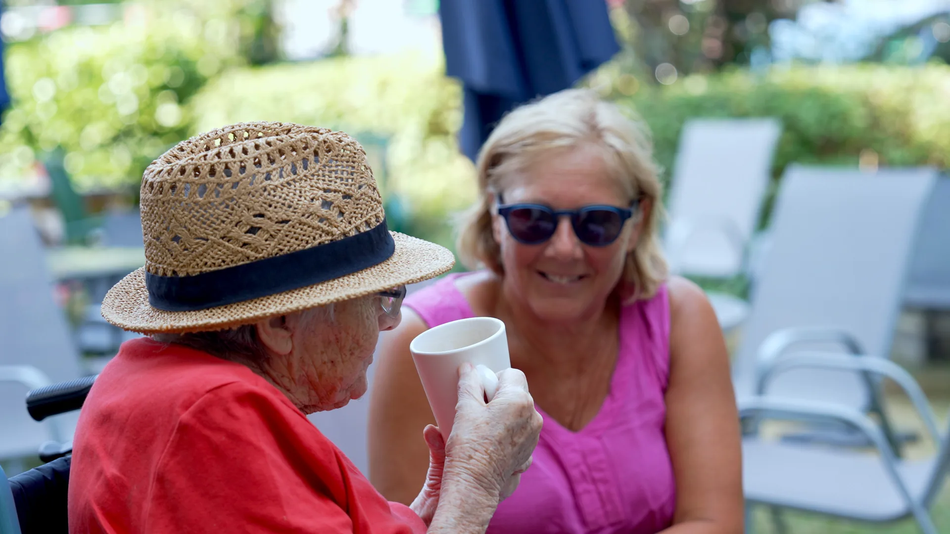 A care home resident chatting with a visiting family member in the garden.