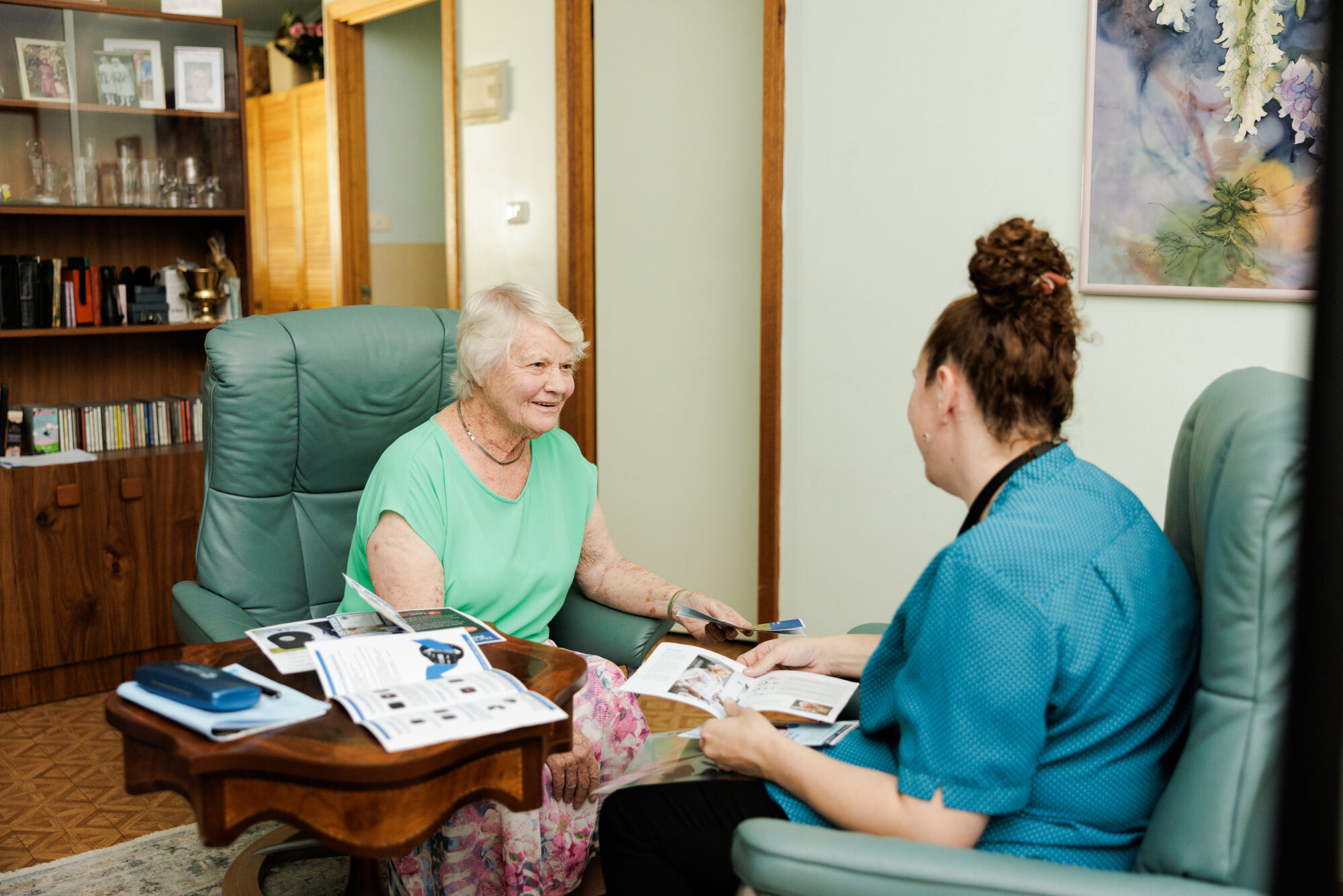 A resident talking things through with a carer over a brochure.