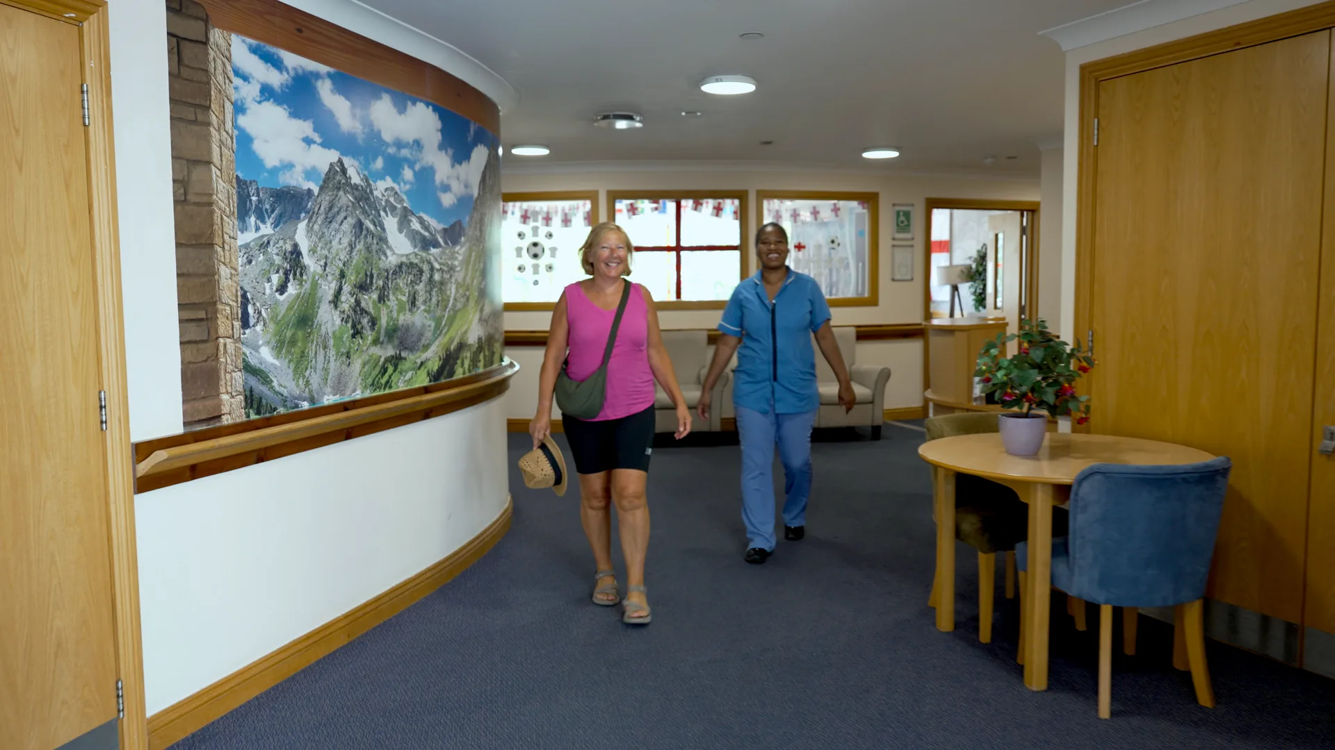 A carer walking a visiting family member through a care home corridor.